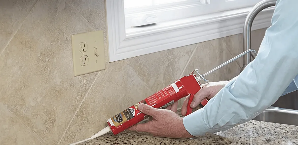 Handyman applying caulk along a kitchen backsplash and countertop seam in St Paul, MN